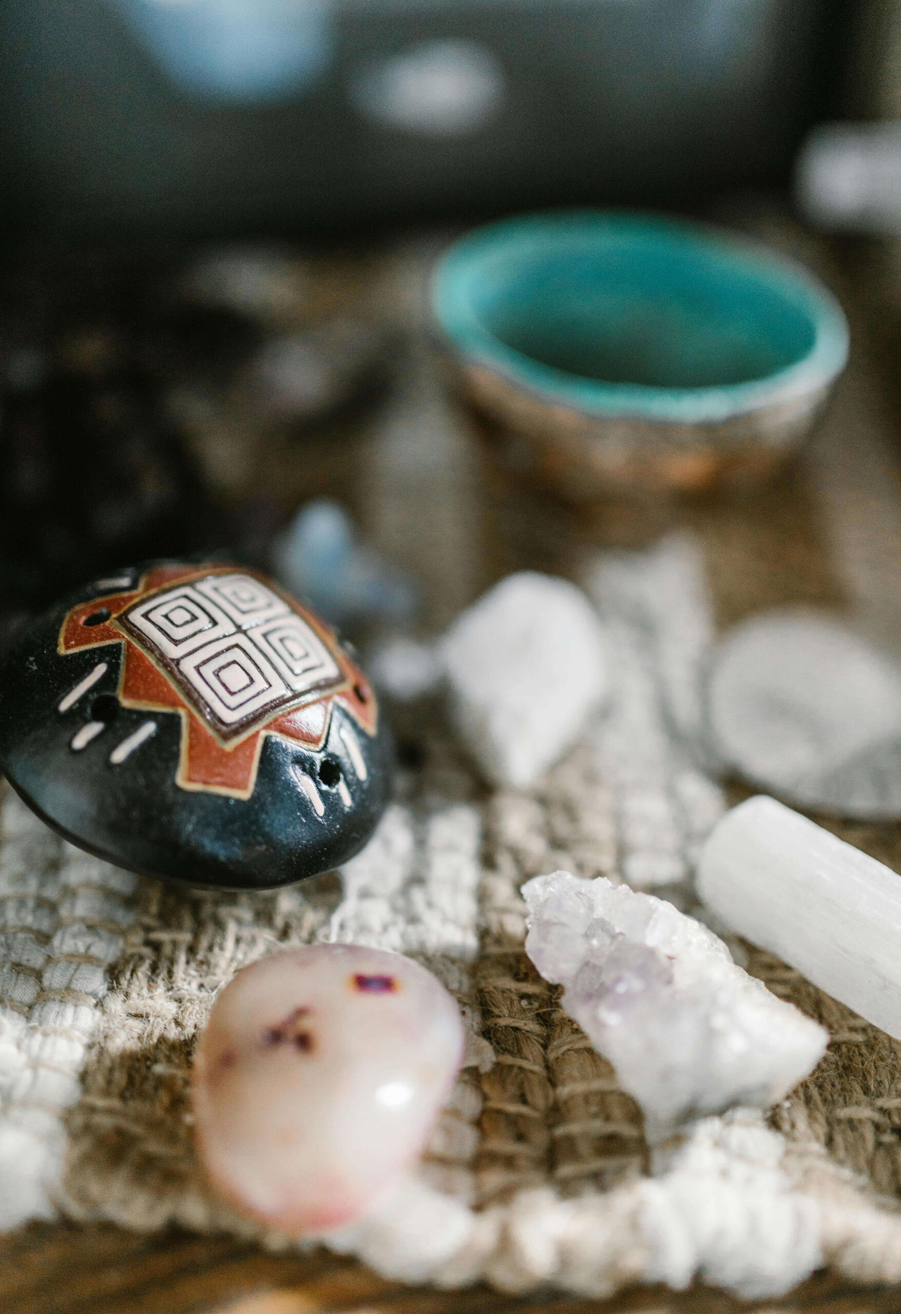 Photo of some white crystals along with a painted rock and bowl.